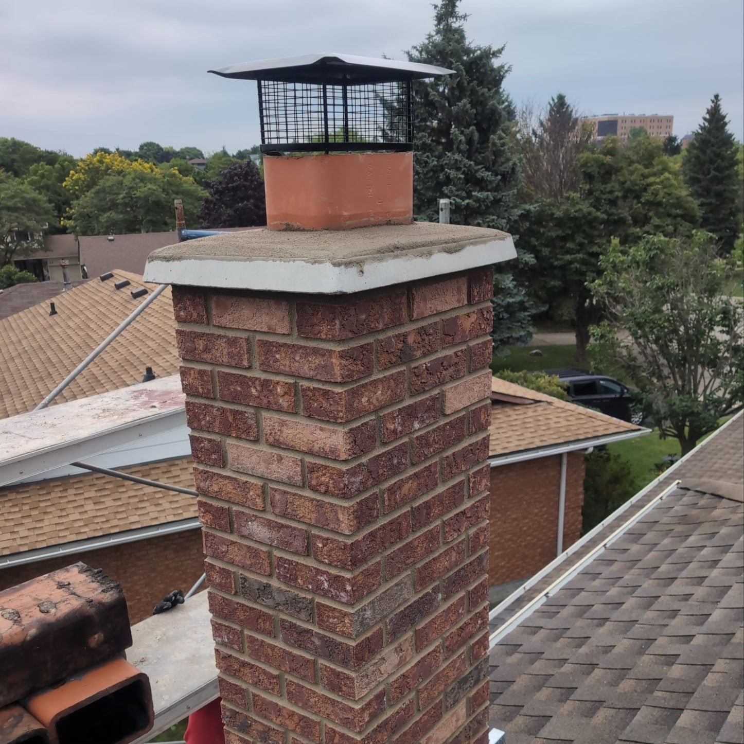 Brick chimney with a metal cap on a residential roof
