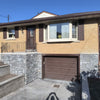 Two-story house with a garage door, stone foundation, and clear blue sky.