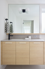 Bathroom vanity with wooden cabinets, mirror, and sink.
