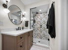 Bathroom with vanity, mirror, and shower with geometric tile design.