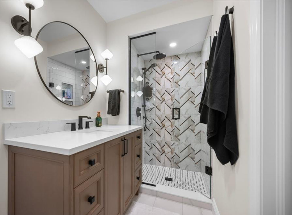 Bathroom with vanity, mirror, and shower with geometric tile design.