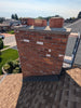 Brick chimney on a roof with a suburban neighborhood in the background