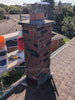 Brick chimney on a roof with construction materials and tools.