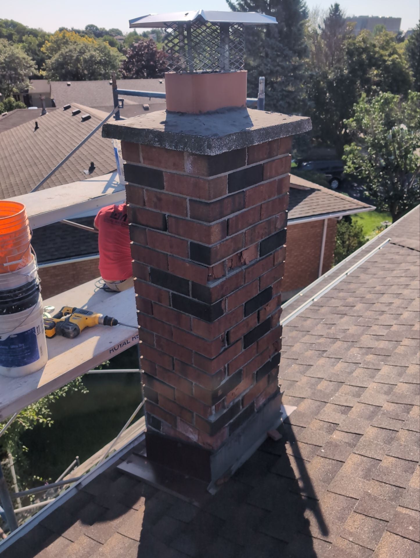 Brick chimney on a roof with construction materials and tools.
