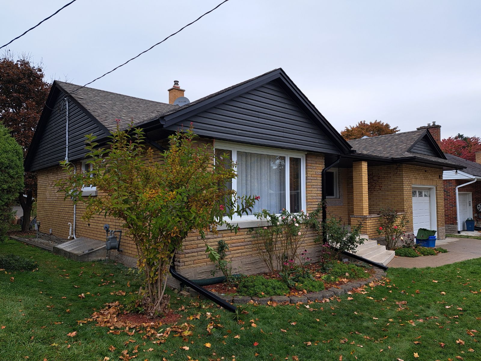 Brick house with a front yard and garden area on a clear day.
