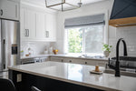 Modern kitchen with white cabinets, stainless steel appliances, and a large window.