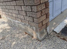 Concrete foundation with a brick wall and a gray door in the background