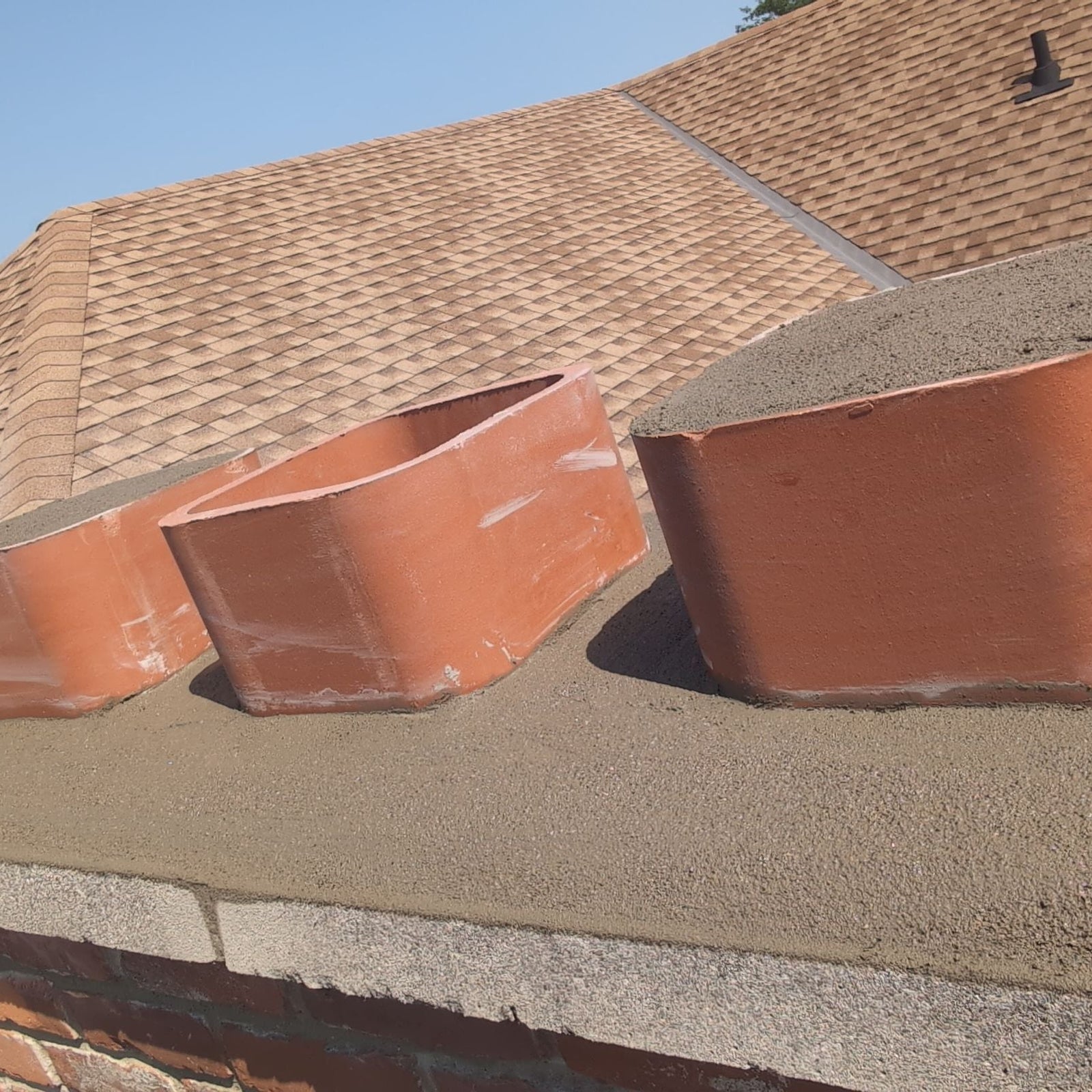 Two copper gutters on a roof with a clear blue sky in the background
