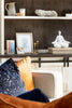 Decorative shelf with books, a photo frame, and a small statue in a cozy living room setting.
