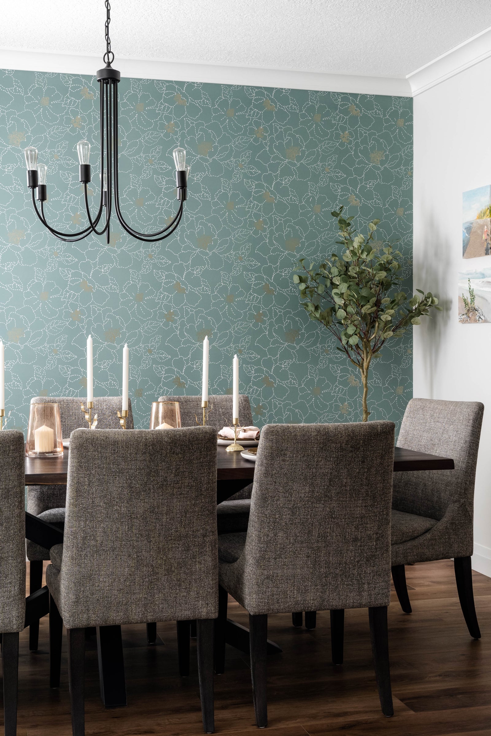 Dining room with a teal patterned wall, chandelier, and gray chairs.