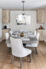 Dining room with a gray table and patterned chairs, wooden cabinets, and a mirror on the wall.