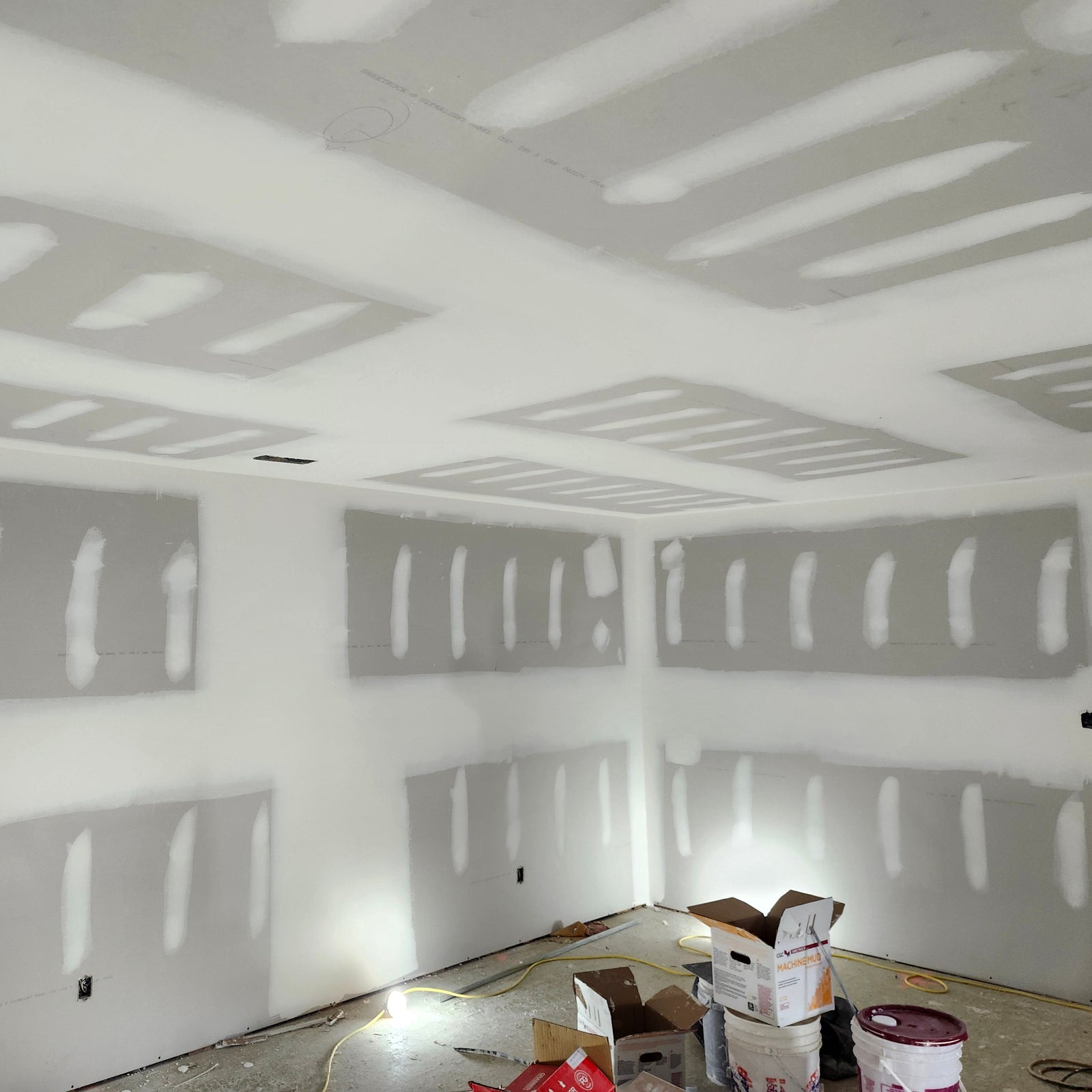 Drywall ceiling installation and wall finishing in residential home under construction with taped joints and joint compound applied