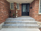 Front entrance of a house with stone steps leading to a black door.