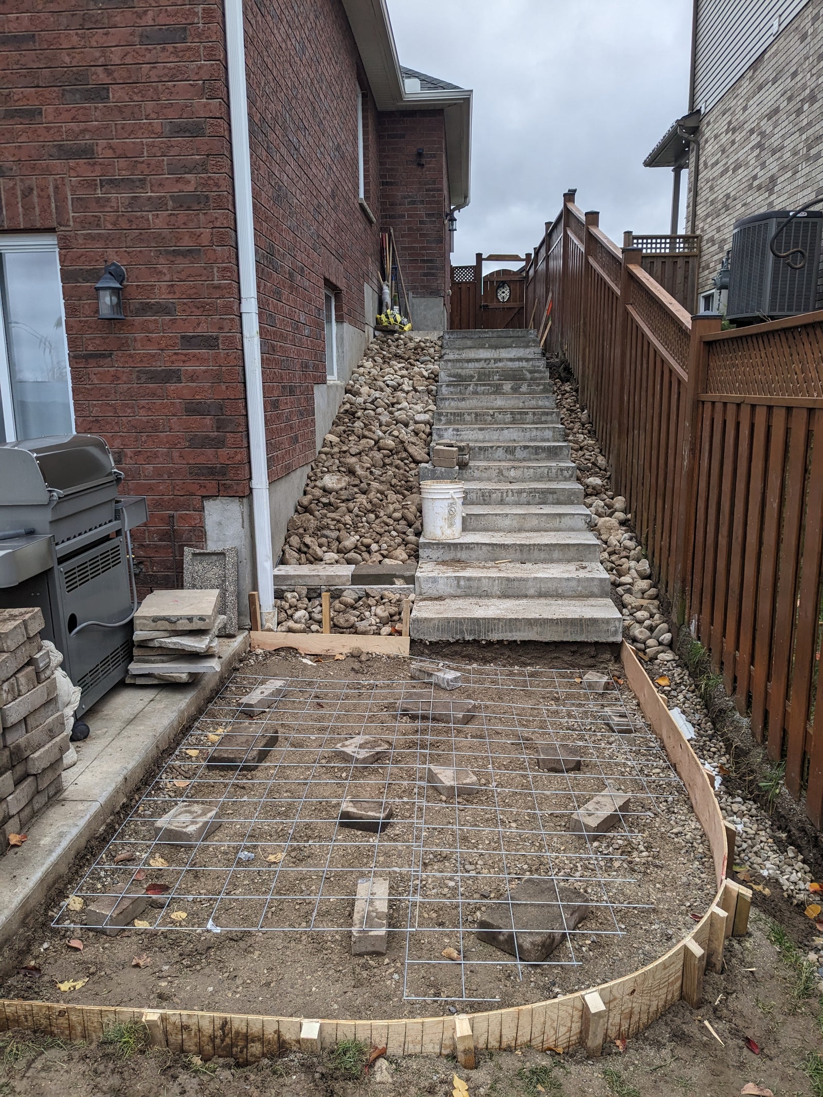 Under construction concrete patio with steps leading up to a house.