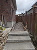 Under construction concrete pathway leading to a house with tools and materials around.