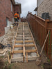 Person working on a set of wooden stairs being built in an outdoor setting.
