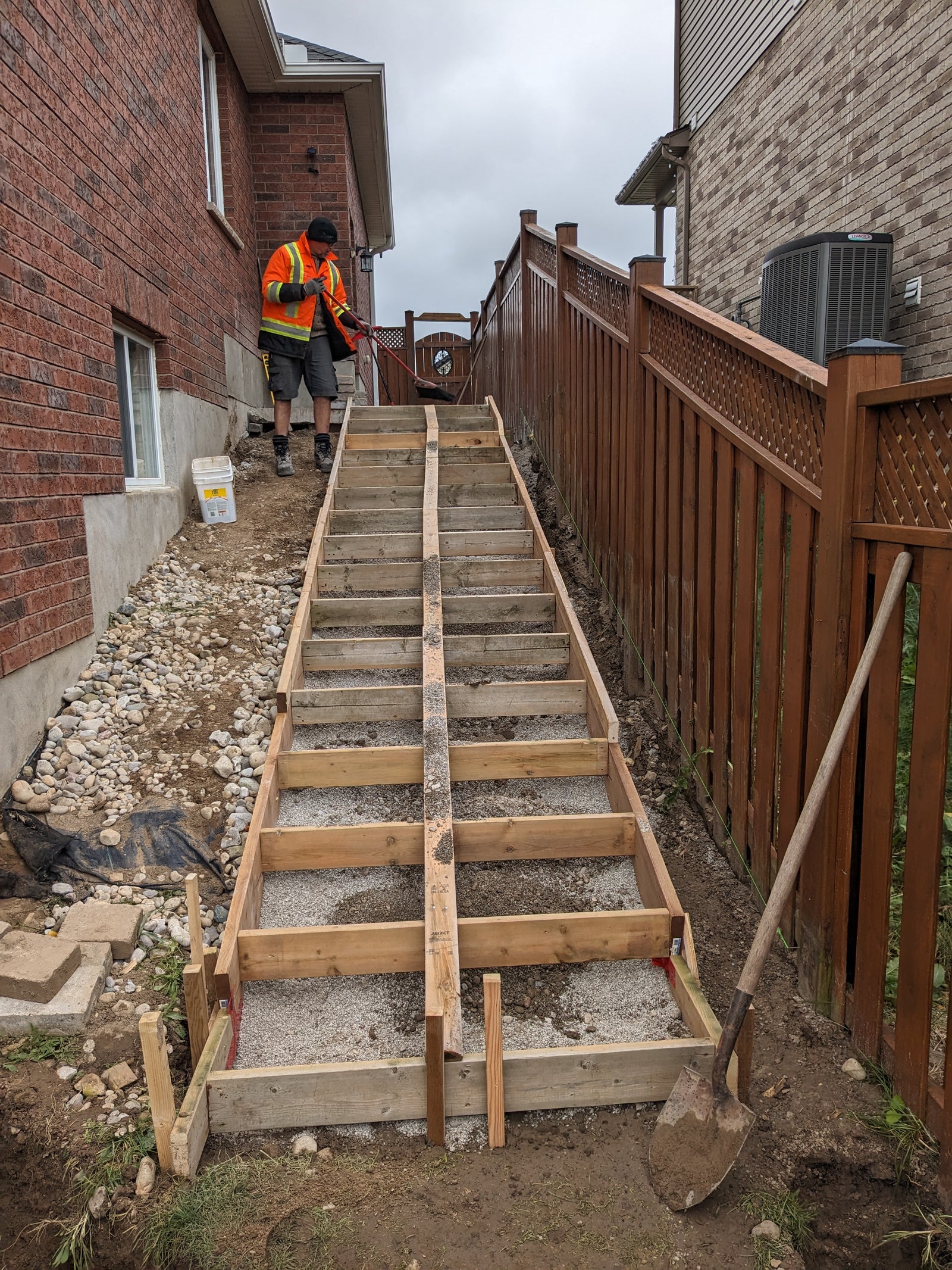 Person working on a set of wooden stairs being built in an outdoor setting.