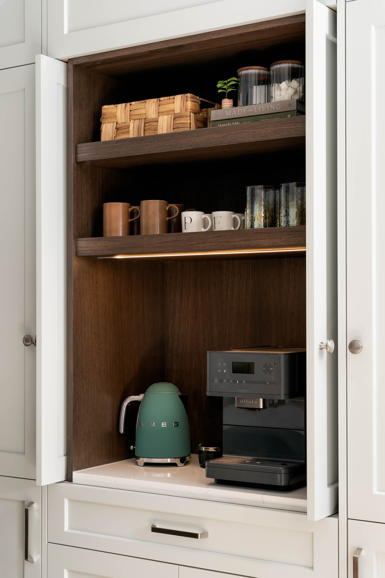 Open kitchen cabinet with coffee-making appliances and supplies