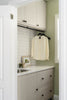 Small laundry room with white cabinets, countertop, and a hanging shirt.