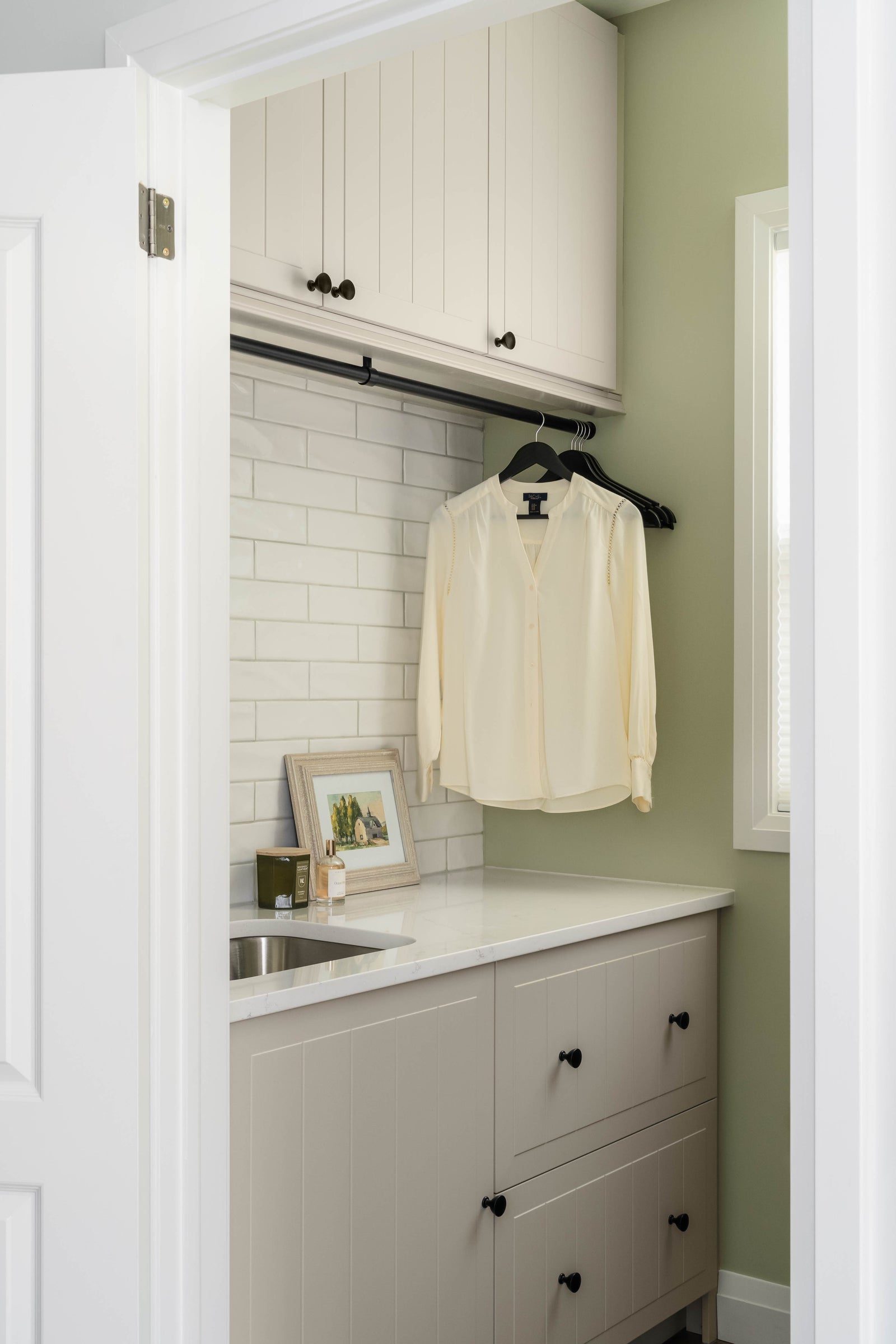 Small laundry room with white cabinets, countertop, and a hanging shirt.