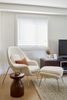 Modern living room with a white armchair, ottoman, and wooden side table.
