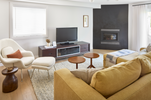 Modern living room with yellow sofa, white armchair, and television.
