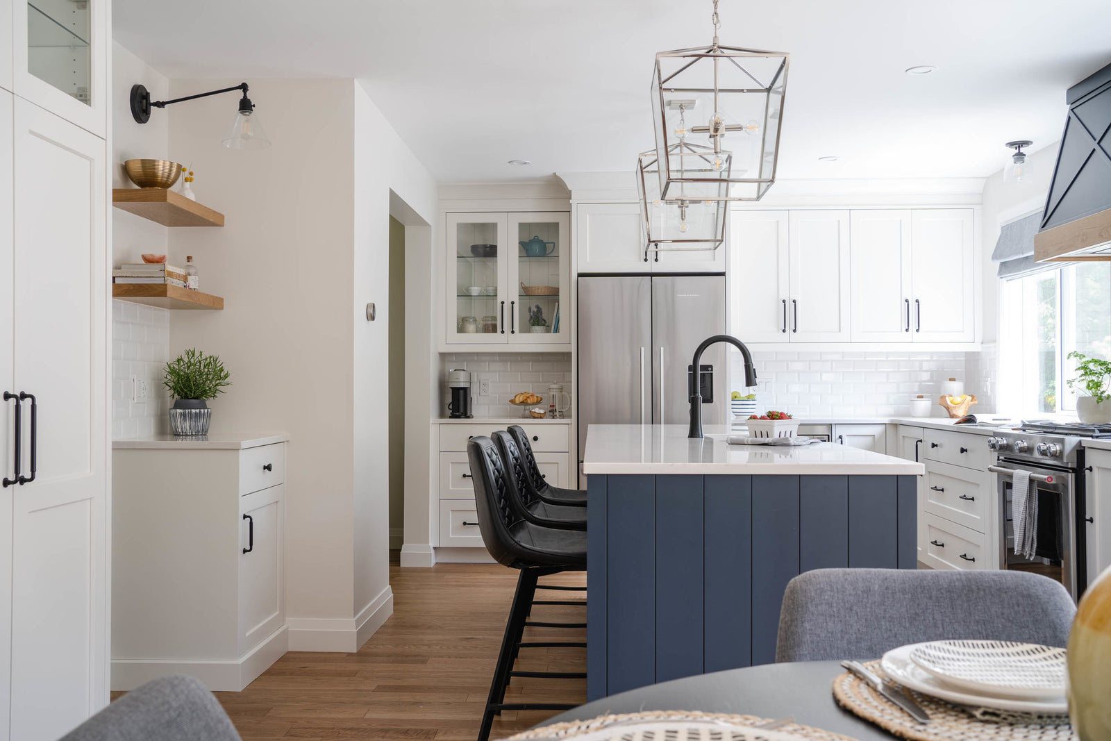 Modern kitchen with blue island, white cabinets, and stainless steel appliances.
