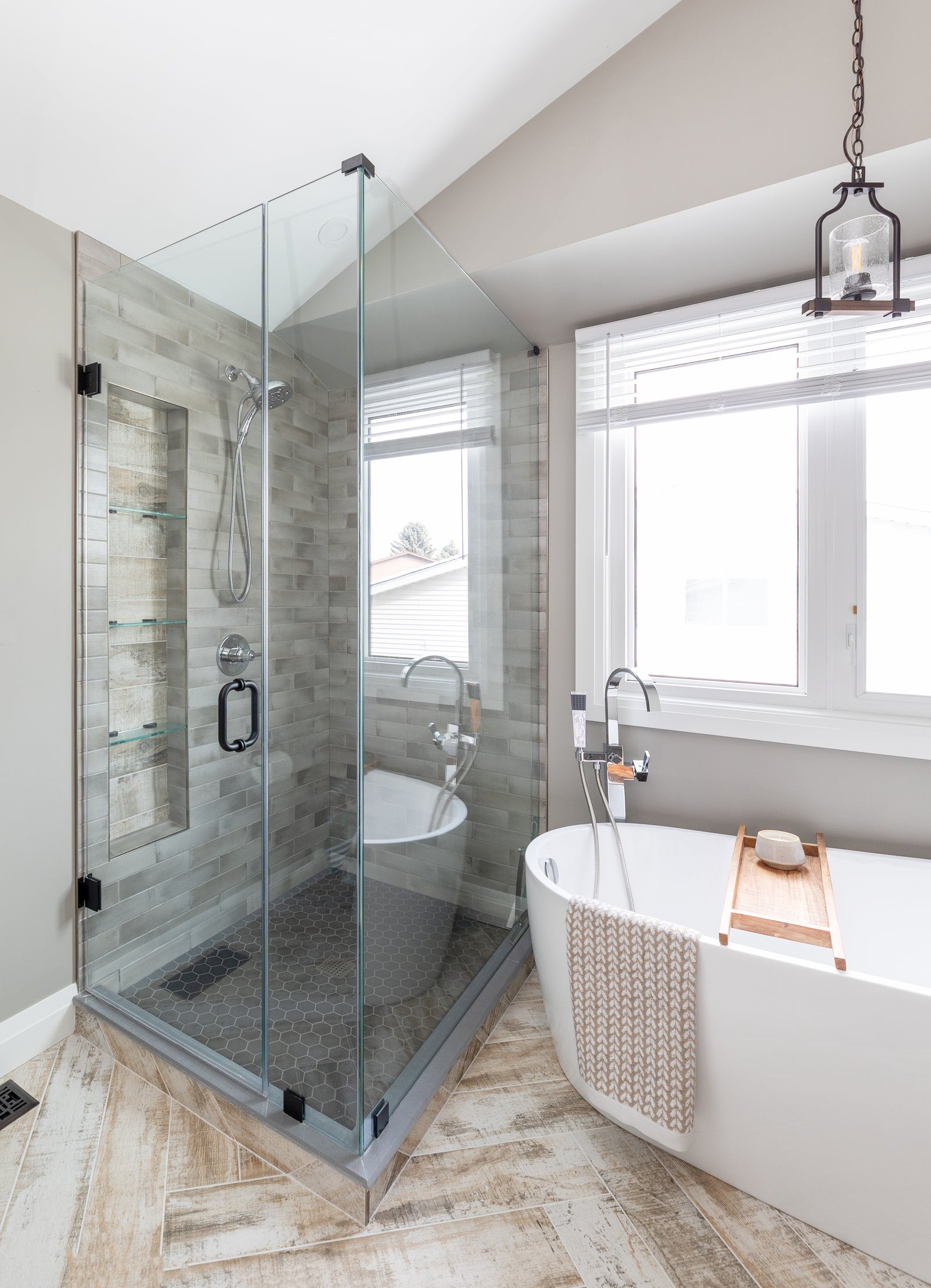 Modern bathroom with glass shower enclosure, freestanding bathtub, and large window.