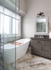 Modern bathroom with freestanding bathtub, wooden floor, and gray vanity.