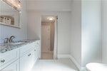 Modern bathroom with white vanity cabinets, granite countertop, brushed nickel faucet, and light tile flooring in residential home