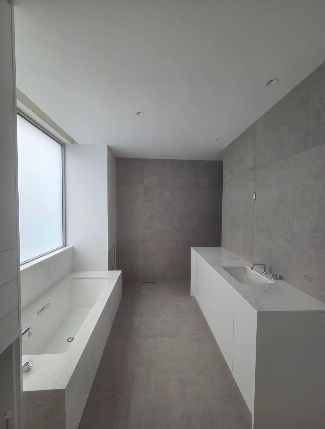 Modern bathroom with concrete floor and walls, featuring a bathtub and sink.