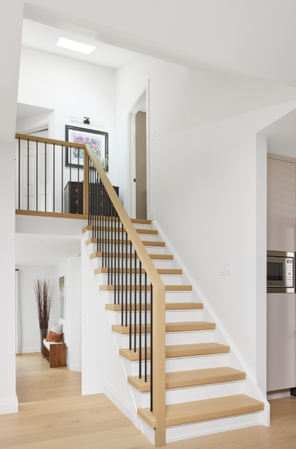 Modern staircase with wooden steps and metal railings in a home interior.