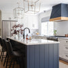 Modern kitchen with a blue island, white cabinets, and stainless steel appliances.