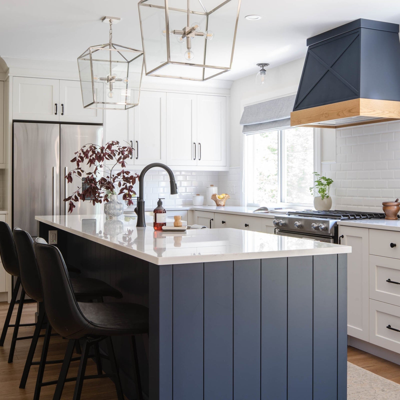 Modern kitchen with a blue island, white cabinets, and stainless steel appliances.