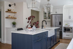 Modern kitchen with blue island, white countertops, and stainless steel appliances.