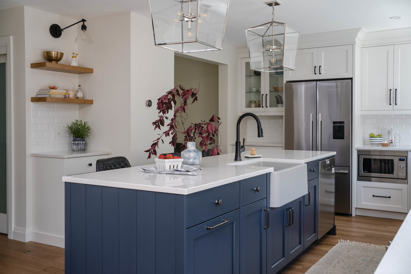 Modern kitchen with blue island, white countertops, and stainless steel appliances.