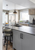 Modern kitchen with gray island, bar stools, and stainless steel appliances.