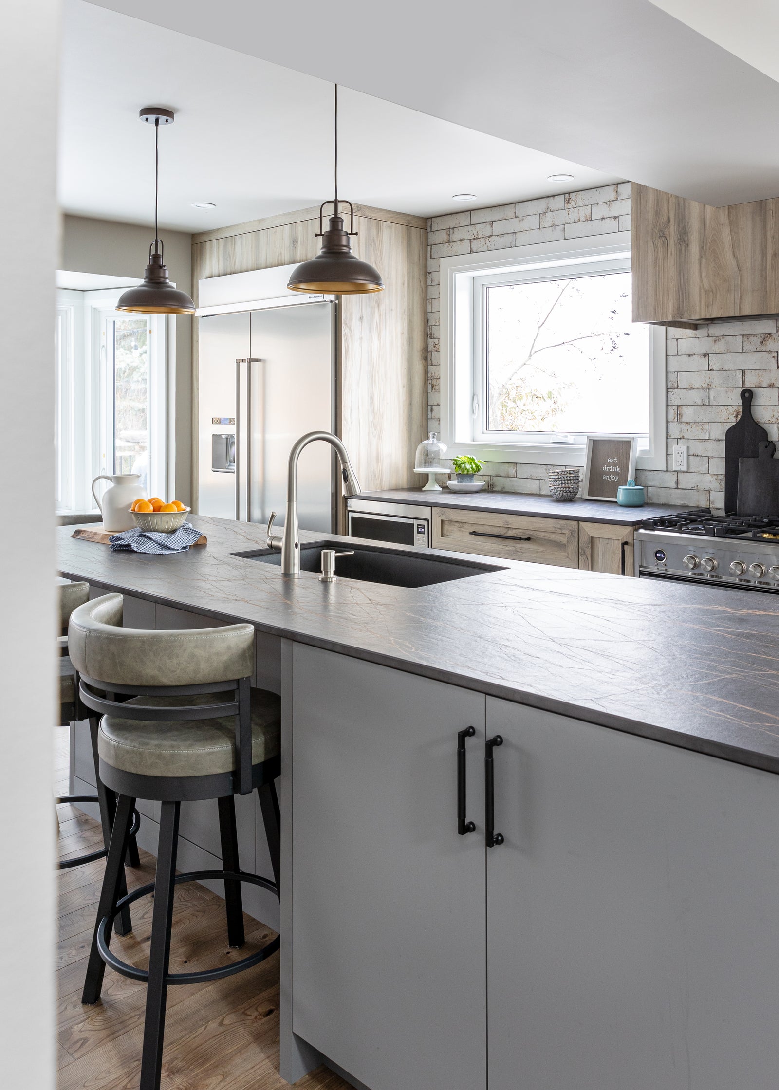 Modern kitchen with gray island, bar stools, and stainless steel appliances.