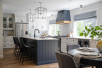 Modern kitchen with gray island, black chairs, and a dining table.