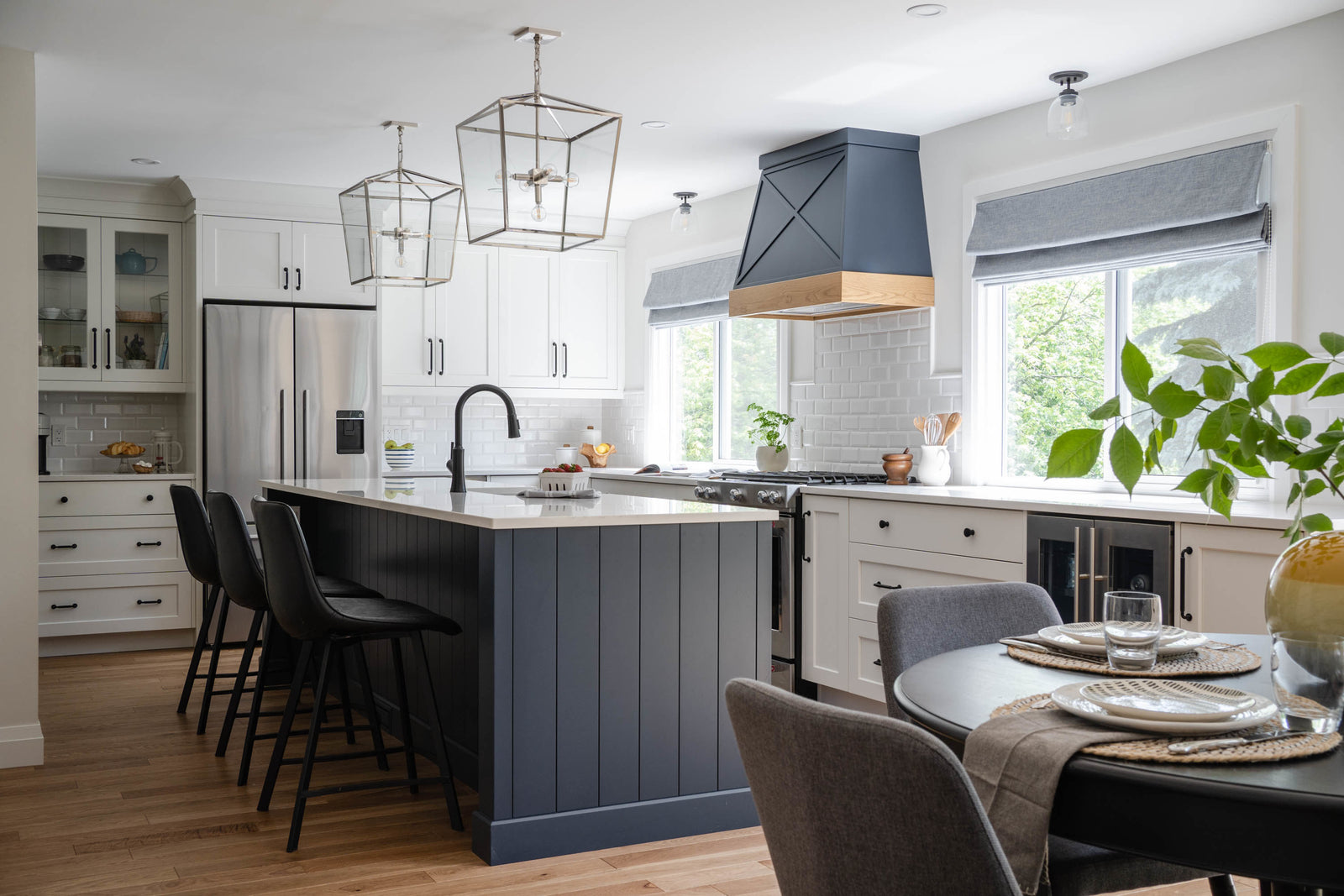 Modern kitchen with gray island, black chairs, and a dining table.