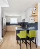 Modern kitchen with green bar stools and a black island.