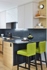 Modern kitchen with dark marble countertop, white cabinets, and green stools.