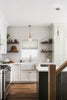 Modern kitchen with white cabinets, subway tile backsplash, and wooden floor.