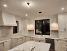 Modern kitchen with white cabinets, marble countertop, and stainless steel appliances.