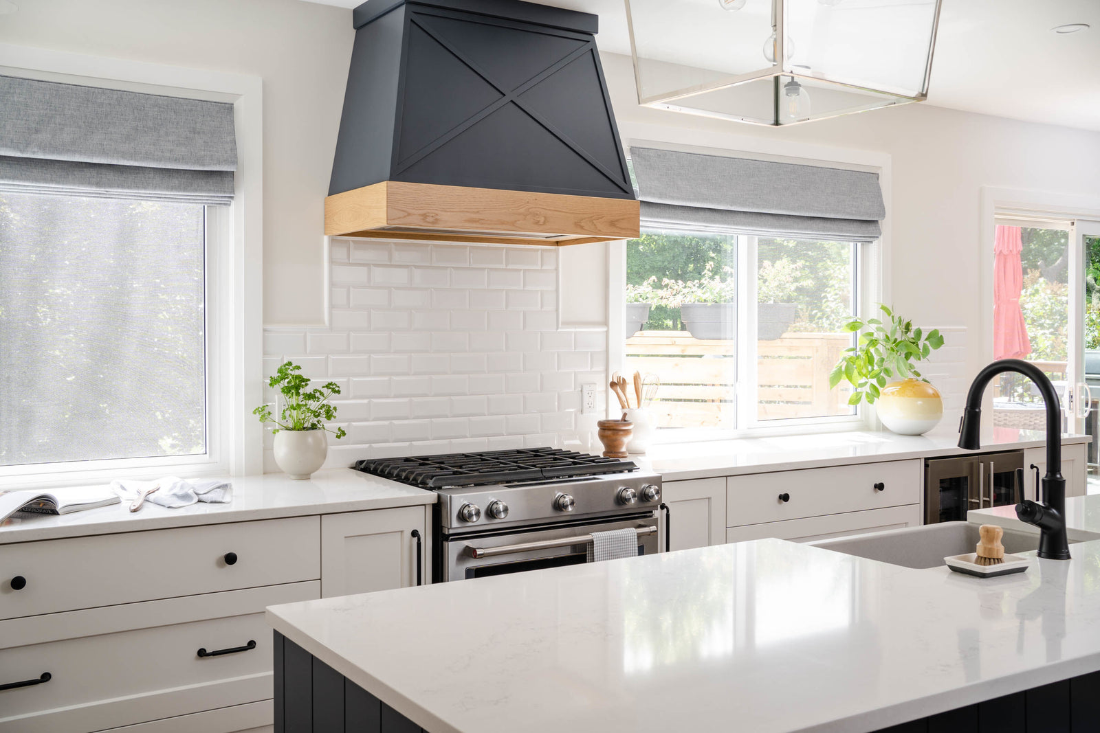 Modern kitchen with white countertops, gray cabinets, and a black range hood.