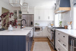 Modern kitchen with white and navy cabinets, stainless steel appliances, and a tiled backsplash.