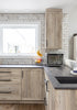 Modern kitchen with wooden cabinets, granite countertops, and a window.