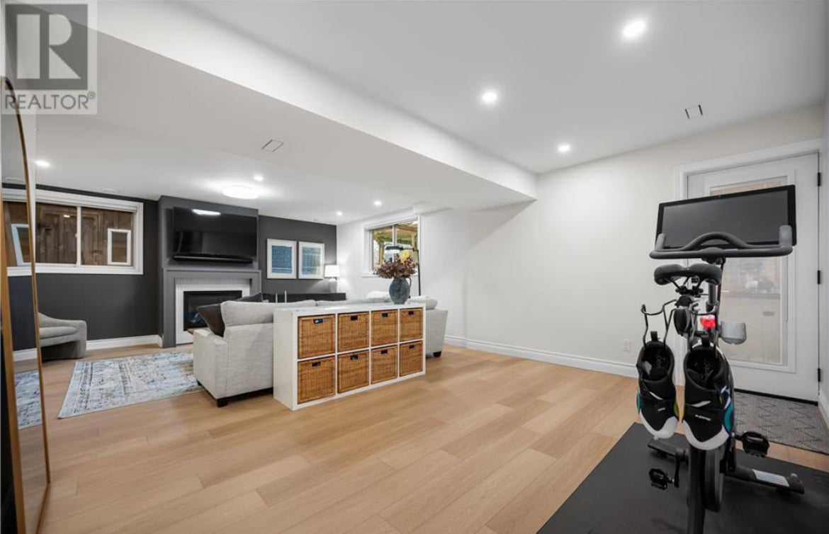 Modern living room with exercise bike, TV, and storage cabinets.