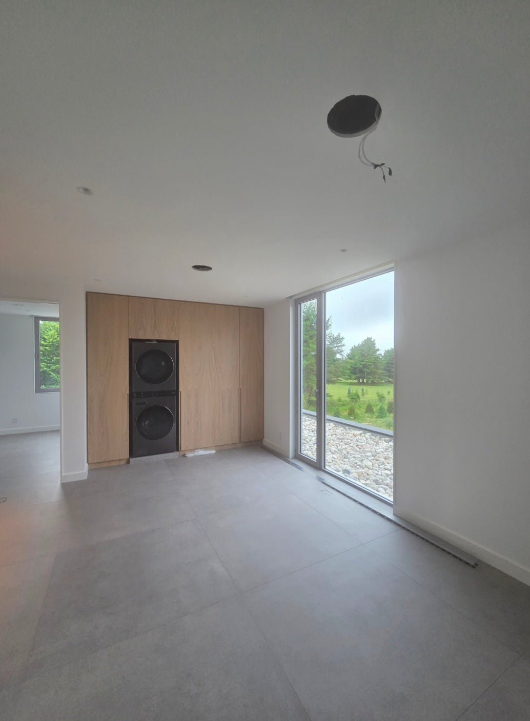 Modern room with wooden paneling and large glass window overlooking a green landscape.