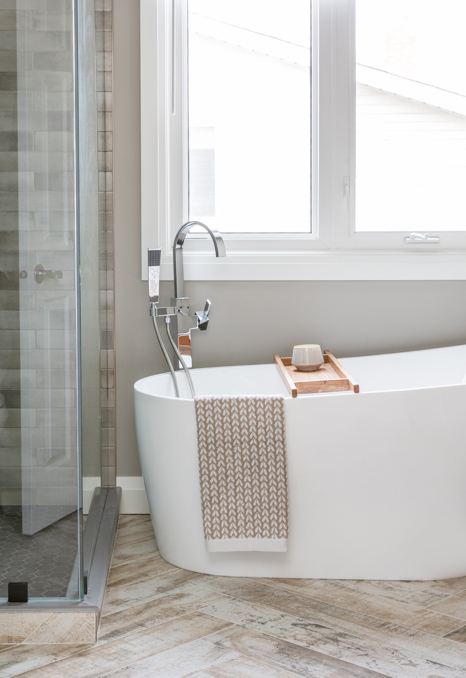 Modern bathroom with a freestanding bathtub, shower, and large window.